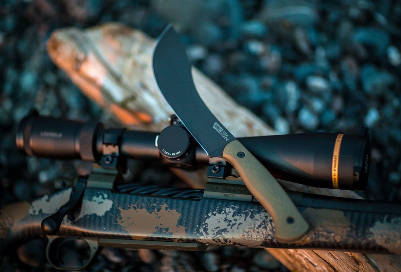 A knife and outdoor gear on a weathered wood surface
